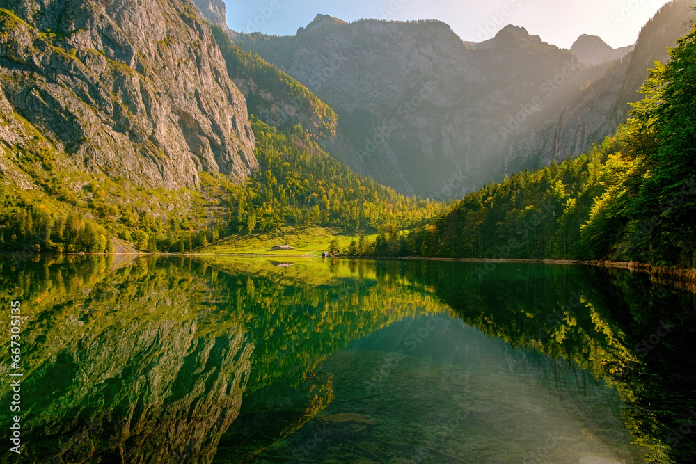 landscape with still lake and mountains in the early morning hour with warm sunlight in early autumn in Bavaria, Germany.