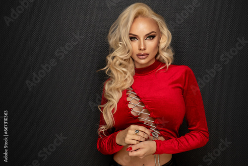 Sensual beautiful blonde woman posing in red shirt. Girl with long curly hair.