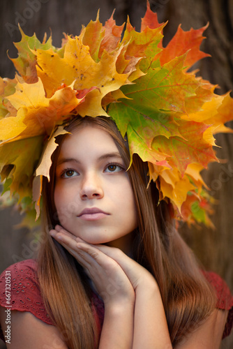 Beautiful teenager girl in the leaves wreath in autumn park