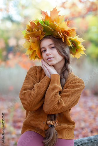 Beautiful teenager girl in the leaves wreath in autumn park