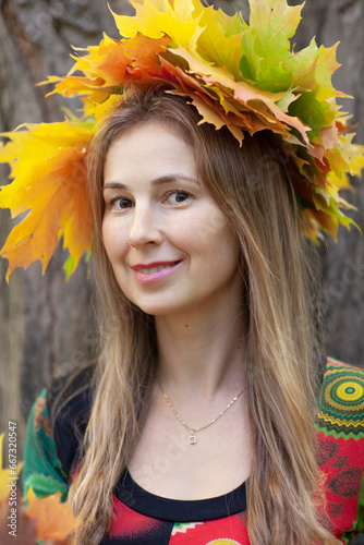 Beautiful happy woman in a park wearing a leaves wreath