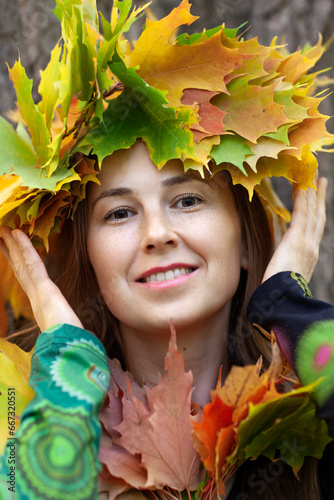 Beautiful happy woman in a park wearing a leaves wreath