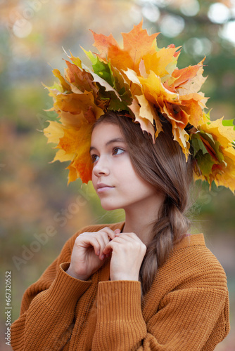 Beautiful teenager girl wearing leaves wreath in autumn park