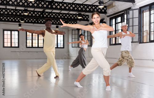 Group of young people learning modern dance movements at class together