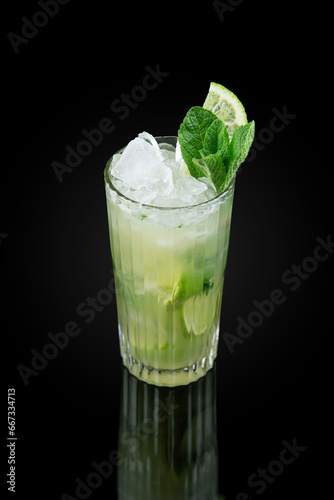 The Mojito. Alcoholic cocktail based on light rum and mint leaves. Glass on dark background with reflection