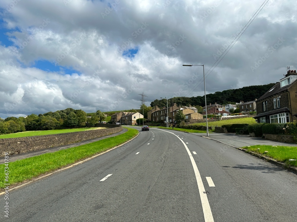 Cottingley Cliffe Road, leading to Bradford, with stone walls, fields, and buildings in, Cottingley, UK