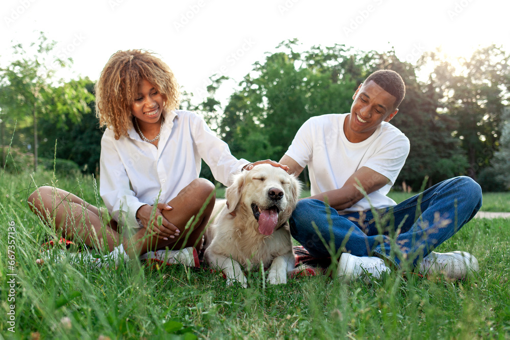 african american happy couple together with dog sit in park in summer and relax african american happy couple together with dog sit in park in summer and relax
