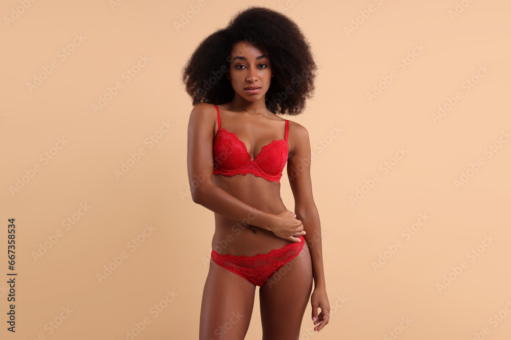 Fototapeta premium Beautiful woman in elegant red underwear on beige background