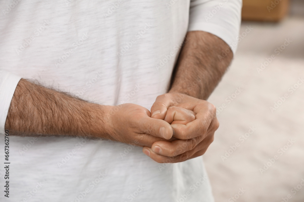 Fototapeta premium Man cracking his knuckles on blurred background, closeup. Bad habit