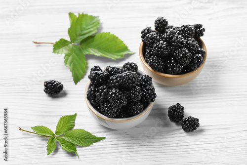 Ripe blackberries and green leaves on white wooden table
