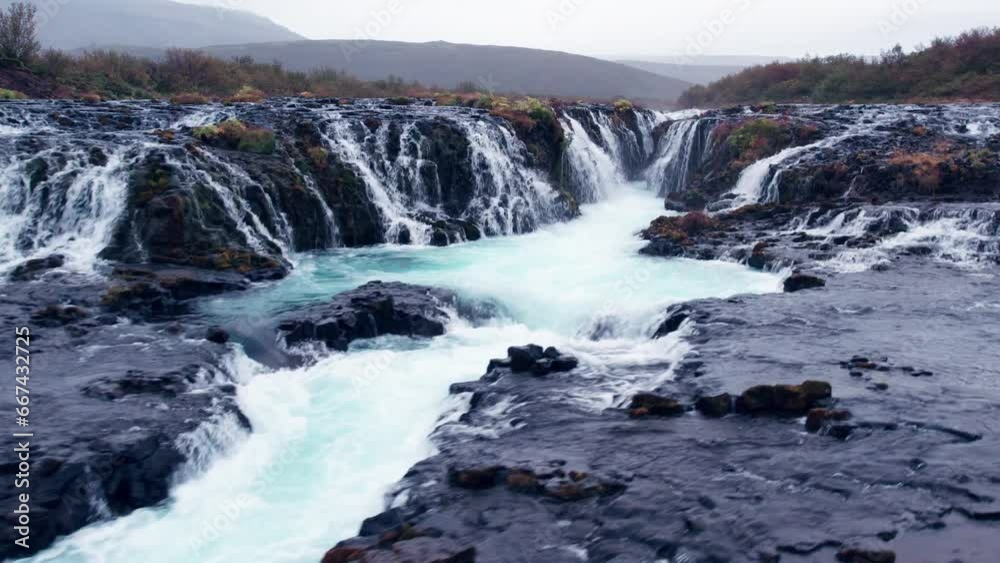 Aerial: Close flyover of Bruarfoss (Brúarfoss) cascading waterfall off the golden circle in southern Iceland that's very picturesque with the beautiful blue cascade of falls into the plunge pool below Aerial: Close flyover of Bruarfoss (Brúarfoss) cascading waterfall off the golden circle in southern Iceland that's very picturesque with the beautiful blue cascade of falls into the plunge pool below