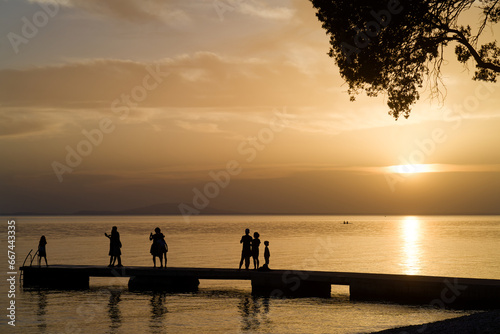 Steg mit Leuten als Silhouetten vor Sonnenuntergang am Mittelmeer, Kroatien