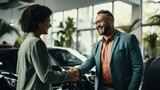 Happy smiling men shake hands with each other in a car dealership against the background of cars.