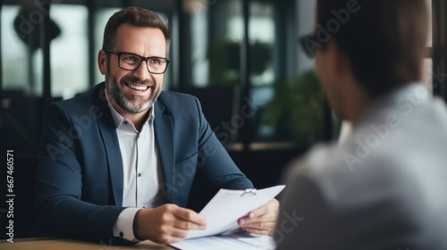 Smiling businessman having discussion with colleague while sitting at office
