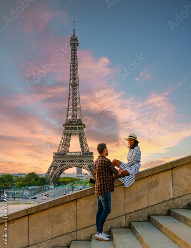 Young couple by Eiffel Tower at Sunrise, Paris Eifel Tower Sunrise man woman in love, valentine concept in Paris the city of love. Men and women visiting the Eiffel Tower. © Fokke Baarssen