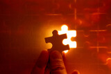Pieces of a jigsaw puzzle filled with orange lights by hand Success concept