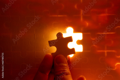 Pieces of a jigsaw puzzle filled with orange lights by hand Success concept