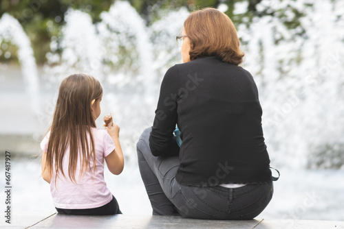 Foto Two people -little girl and her grandmother seated, conversing and eating icecre