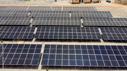 Aerial low sliding left showing dusty and clean bifacial solar panel arrays at NAWEC TBEA Jambur PV power plant under construction photo