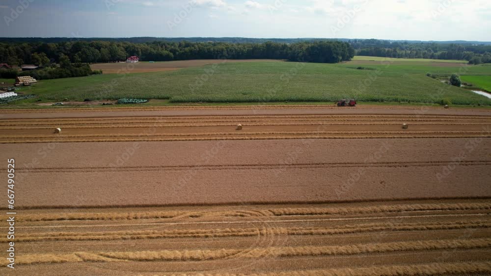 Aerial view of a tractor harvesting working in a wheat field farmland in countryside Poland Aerial view of a tractor harvesting working in a wheat field farmland in countryside Poland