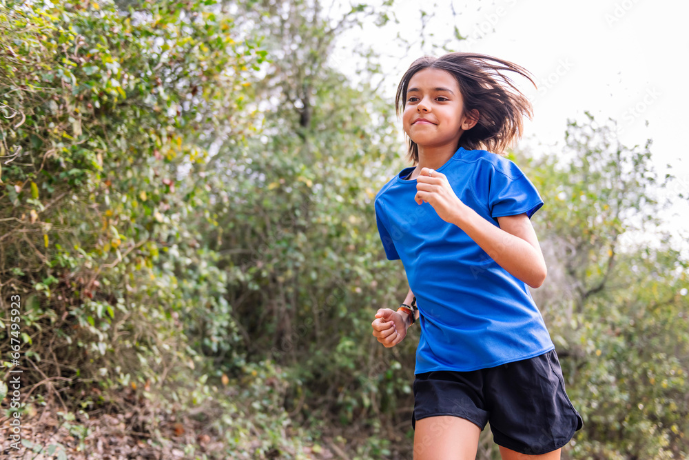 kid practicing trail running in the forest, concept of sport in nature and healthy lifestyle for children, copy space for text