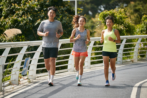 three young asian adults running jogging outdoors