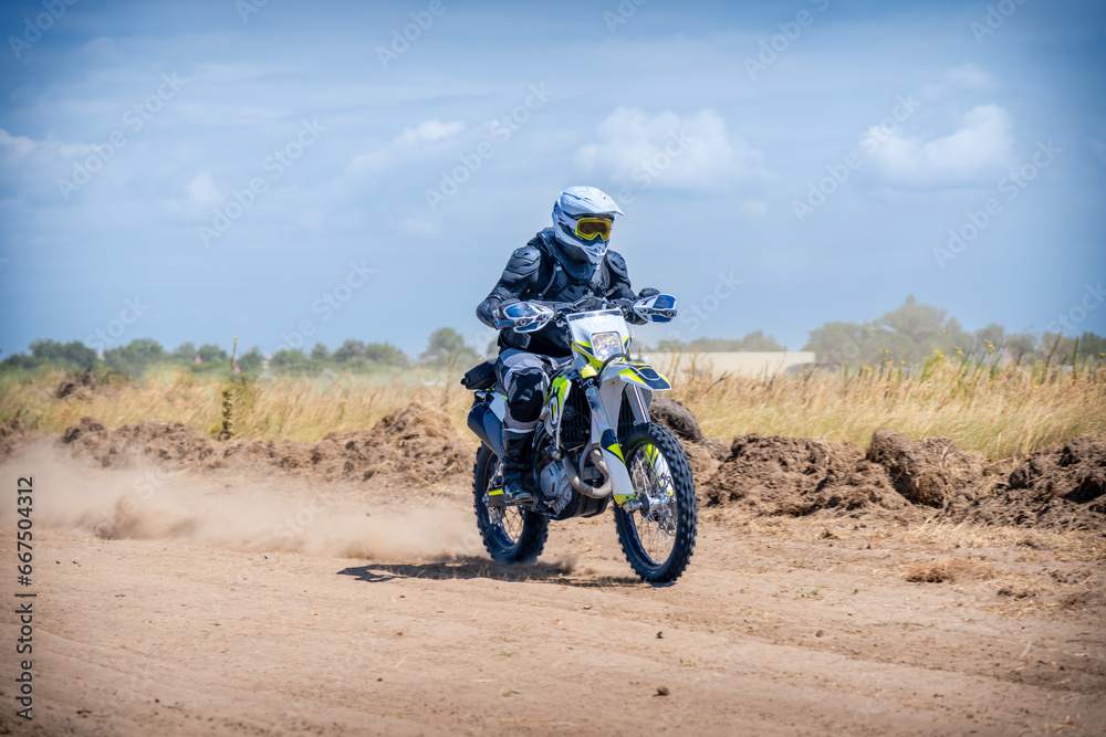 Enduro bike racer driving on dirt motocross dust track