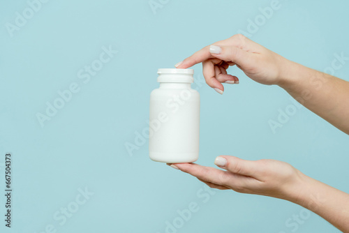 Woman's hand holds white plastic tube. Bottle for pill, capsule or supplement. Product branding mockup