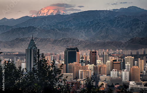 Fototapeta Naklejka Na Ścianę i Meble -  The sunset view of the urban skyline of Urumqi in Xinjiang and the Bogeda Peak in the distance