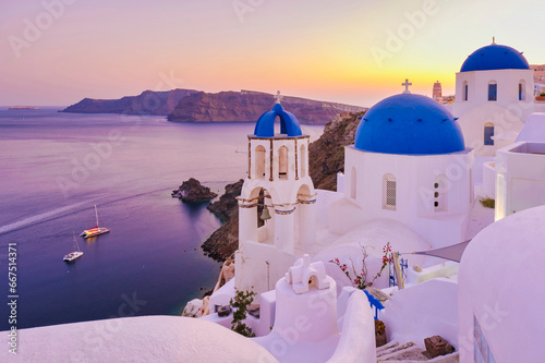 White churches an blue domes by the ocean of Oia Santorini Greece, a traditional Greek village in Santorini during summer at sunset, streets of Oia Santorini