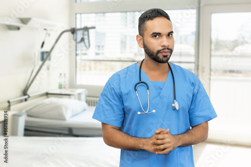 Handsome hispanic male nurse or doctor with beard and stethoscope at hospital room