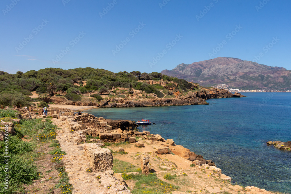Ruins of the Roman Archeological Park of Tipaza ( Tipasa ), Algeria. The Mediterranean sea and the Mount Chenoua in the background. Boat and people.