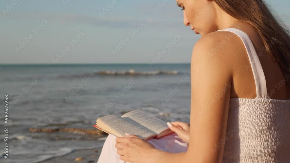 Beautiful woman reading book on sea beach at sunrise. Camera moving down Beautiful woman reading book on sea beach at sunrise. Camera moving down