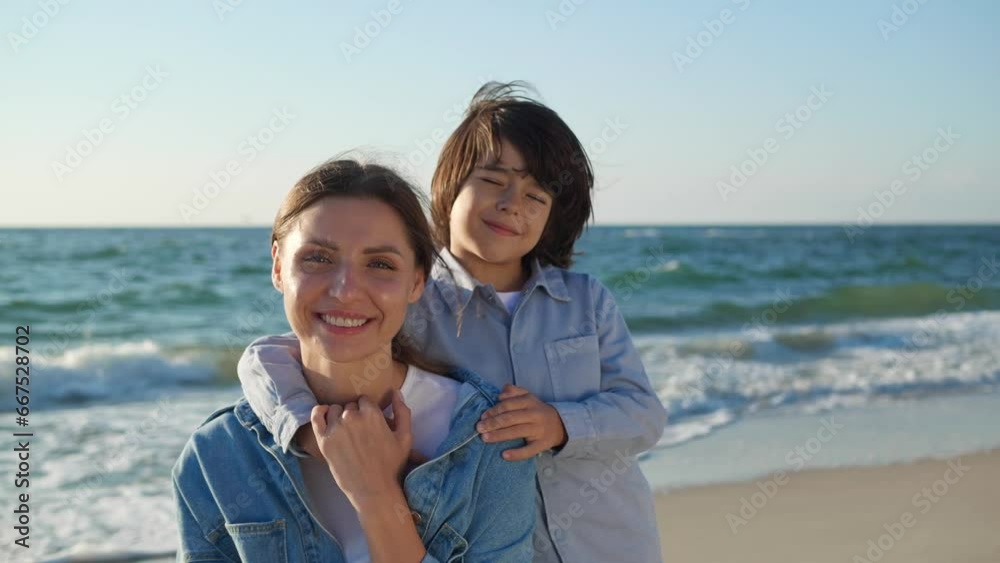 Happy mother with her son on beach near sea. Camera moving around them Happy mother with her son on beach near sea. Camera moving around them