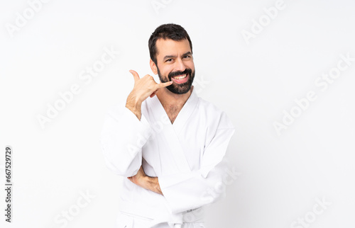 Young man doing karate over isolated white background making phone gesture. Call me back sign