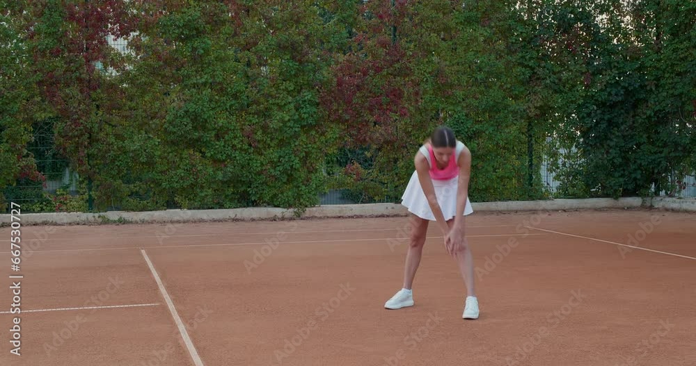 Beautiful woman in stylish sportswear warming up before game at tennis court