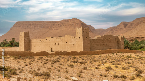 Traditional Moroccan fortress made out of clay with high clay walls in the Atlas mountain gorge by Ziz river, Morocco photo