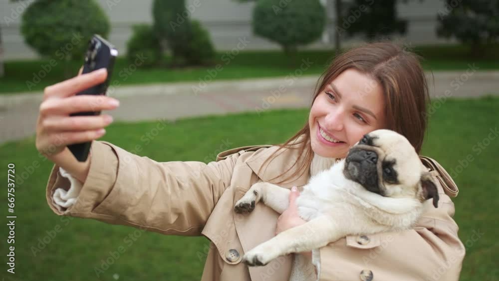 Attractive woman with her cute pug taking selfie on street