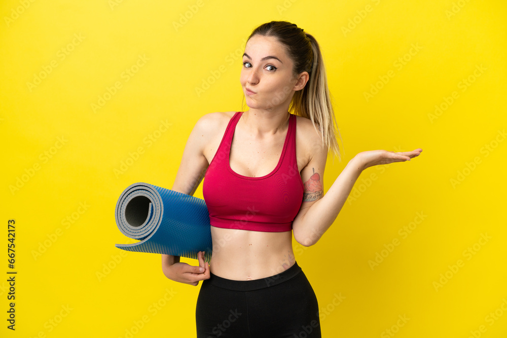 Young sport woman going to yoga classes while holding a mat having doubts while raising hands Young sport woman going to yoga classes while holding a mat having doubts while raising hands