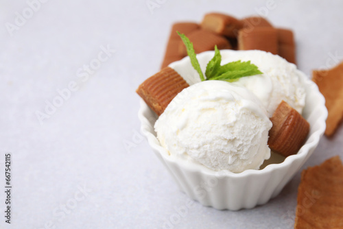 Scoops of tasty ice cream with mint and caramel candies on white table, closeup. Space for text
