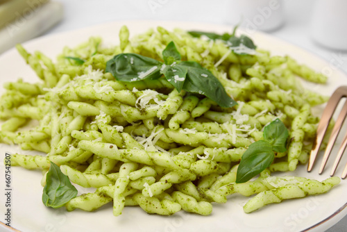 Plate of delicious trofie pasta with pesto sauce, cheese and basil leaves on table, closeup
