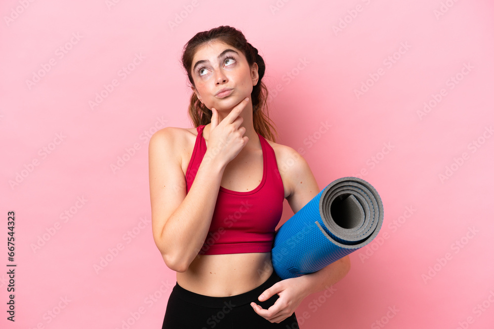 Young sport woman going to yoga classes while holding a mat having doubts Young sport woman going to yoga classes while holding a mat having doubts
