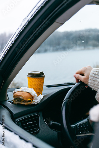burger and coffee mug at car dashboard