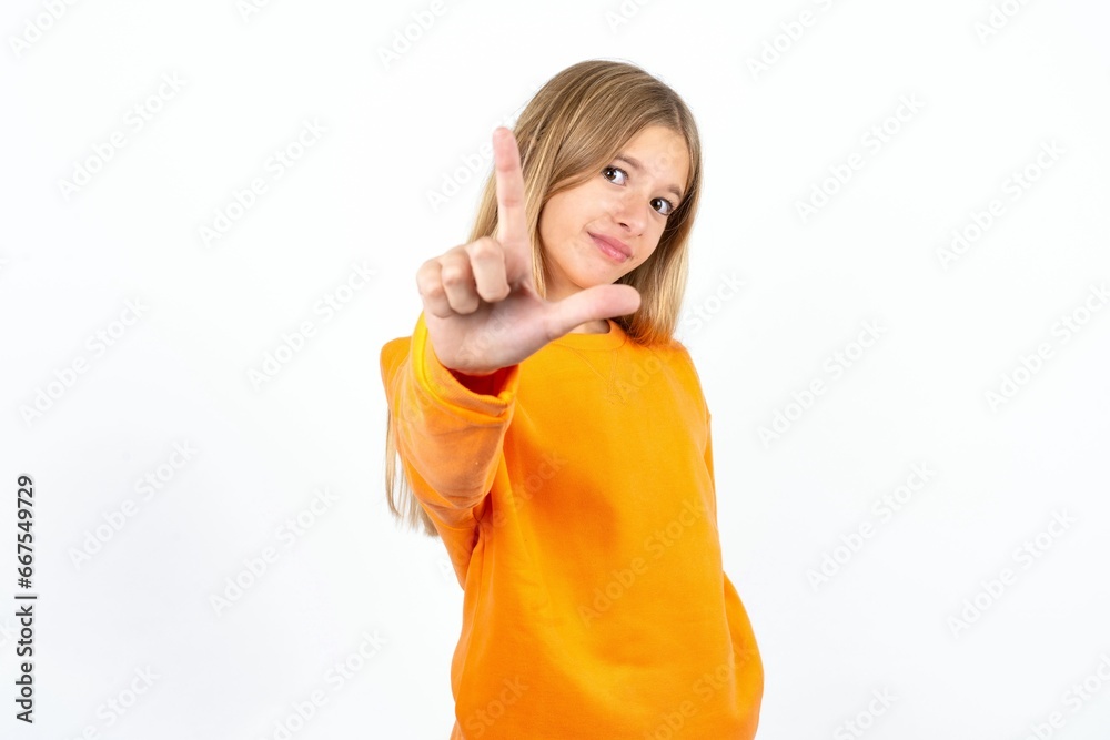 Beautiful teen girl making fun of people with fingers on forehead doing loser gesture mocking and insulting. Beautiful teen girl making fun of people with fingers on forehead doing loser gesture mocking and insulting.