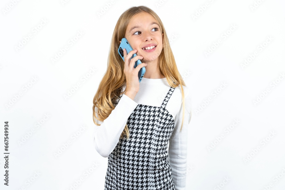 Pleasant looking happy Beautifu blonde kid girl has nice telephone conversation and looks aside, has nice mood and smiles positively while talks via cell phone Pleasant looking happy Beautifu blonde kid girl has nice telephone conversation and looks aside, has nice mood and smiles positively while talks via cell phone