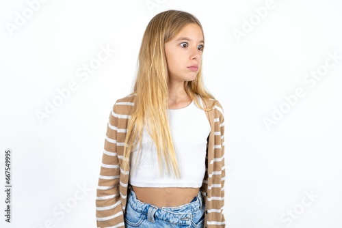 Beautiful teen girl stares aside with wondered expression has speechless expression. Embarrassed model looks in surprise photo