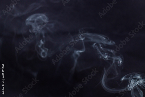 incense smoke swirls to the side on a dark gray background 