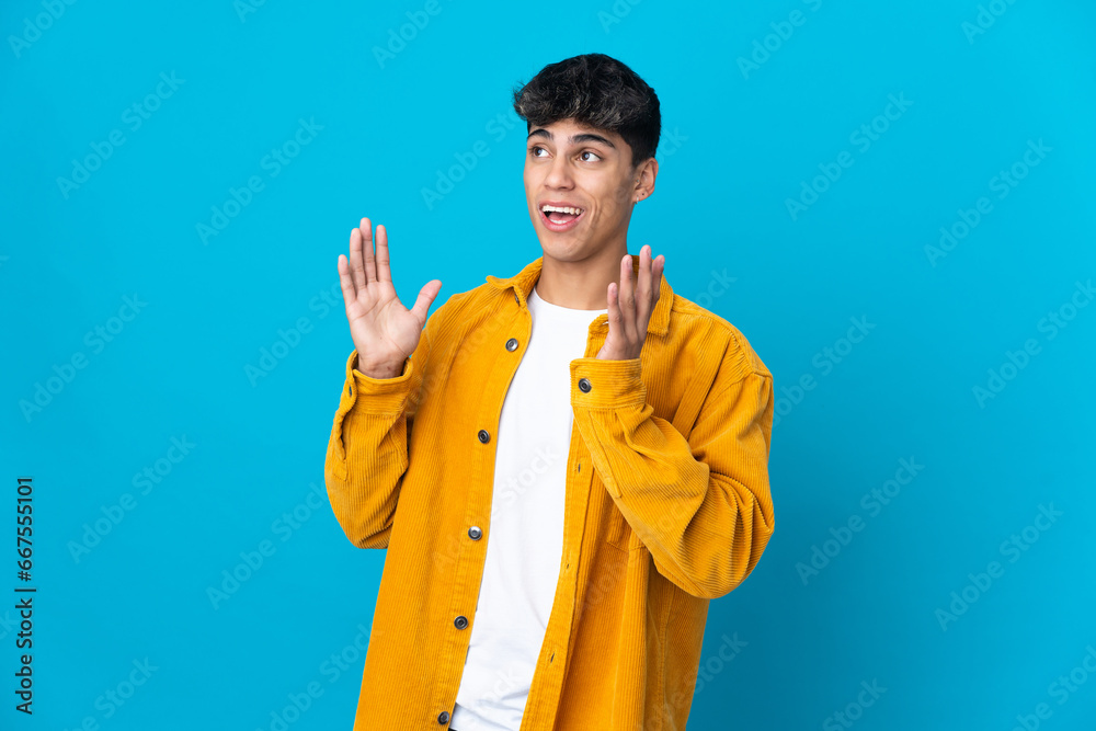 Young man over isolated blue background with surprise facial expression Young man over isolated blue background with surprise facial expression
