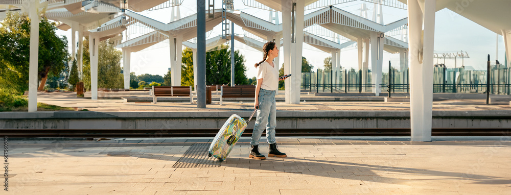 Web banner of modern trip. Side view of young woman walking with her luggage and using cellphone. Copy space. Concept of modern travel and vacation