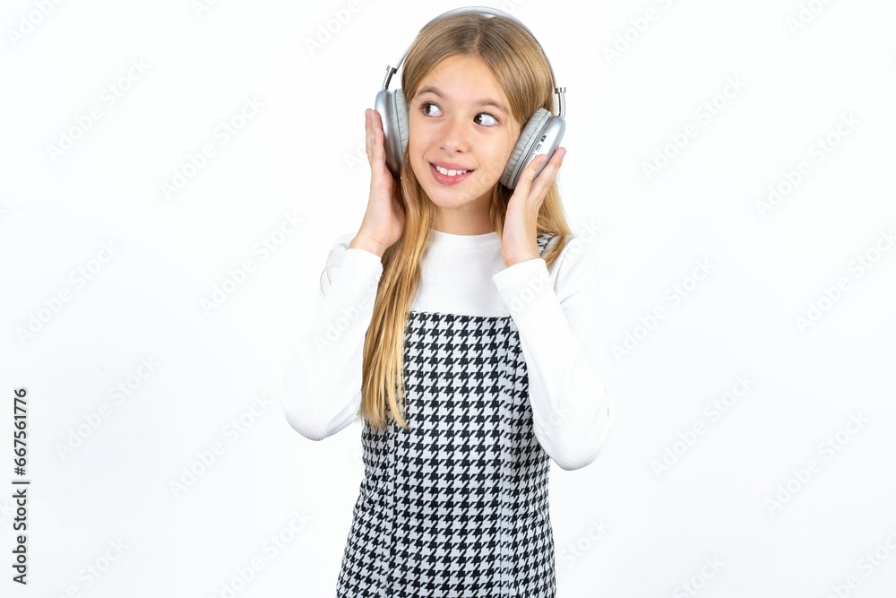 Joyful Beautiful caucasian teen girl sings song keeps hand near mouth as if microphone listens favorite playlist via headphones Joyful Beautiful caucasian teen girl sings song keeps hand near mouth as if microphone listens favorite playlist via headphones
